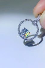 Close-up of a diamond ring held by a hand on a light gray background