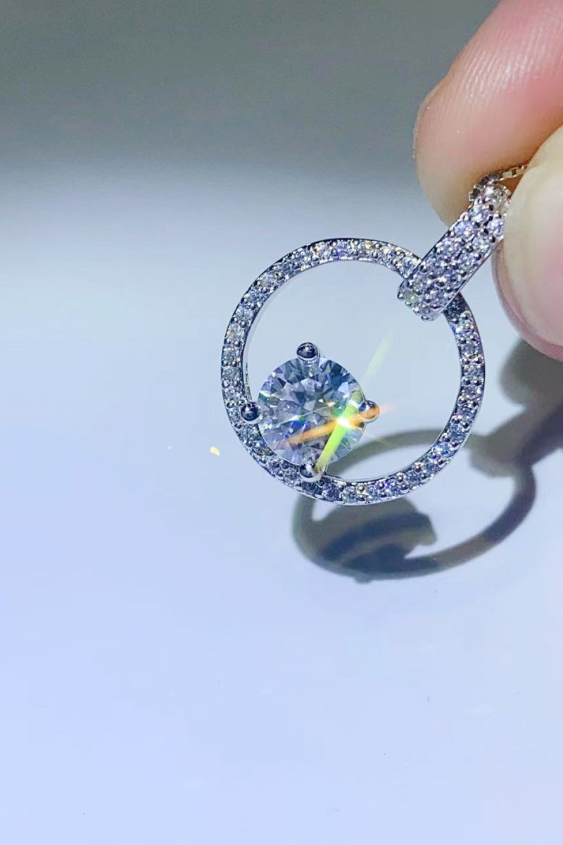 Close-up of a diamond ring held by a hand on a light gray background