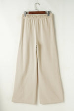 Beige wide-leg pants on a hanger against a white background
