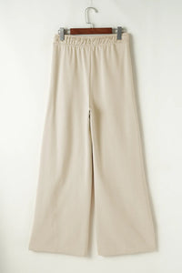 Beige wide-leg pants on a hanger against a white background