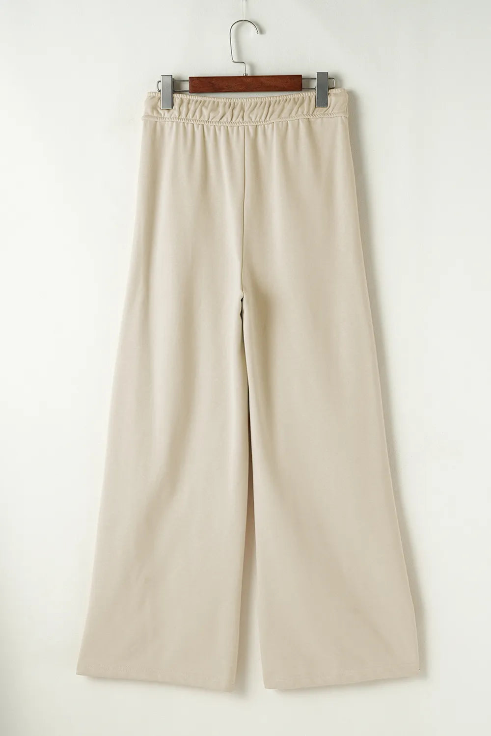Beige wide-leg pants on a hanger against a white background