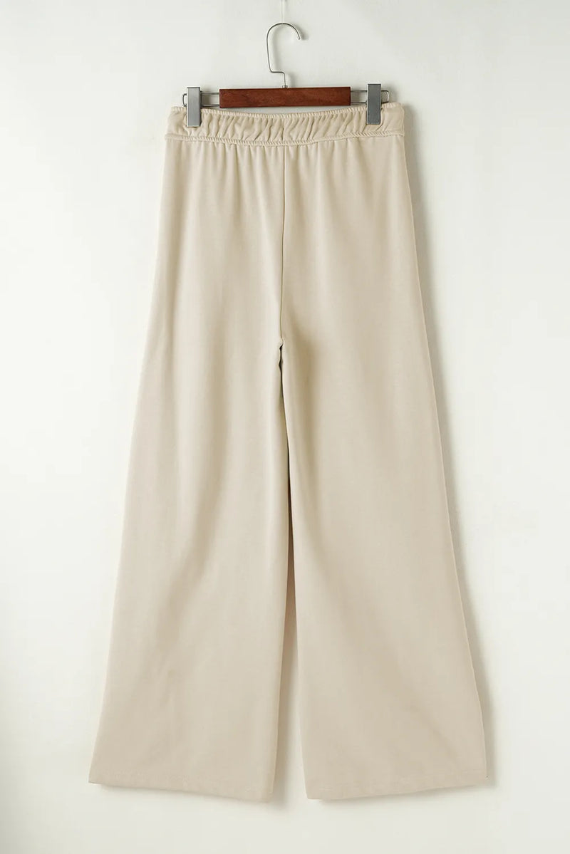 Beige wide-leg pants on a hanger against a white background
