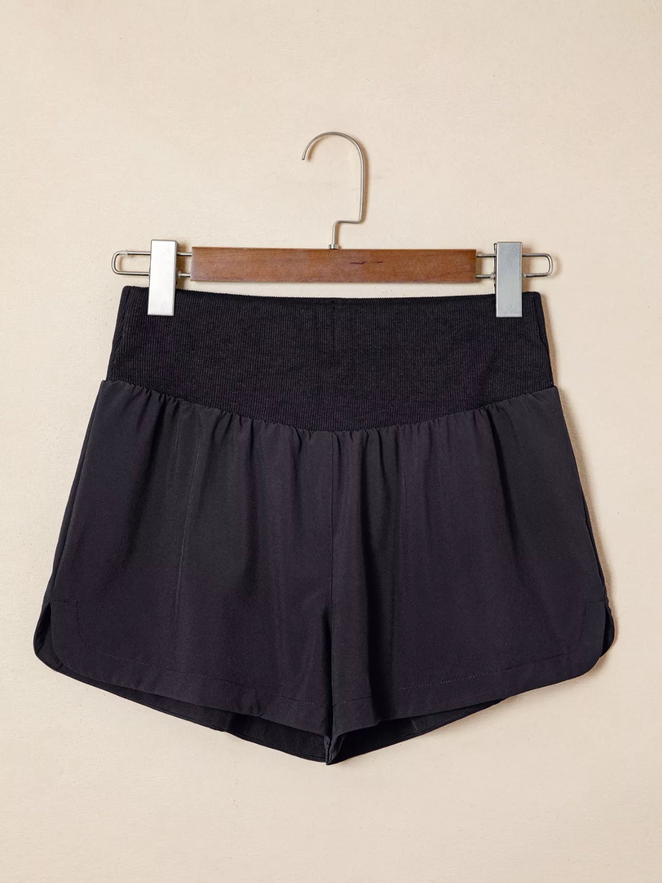 Black shorts on a hanger against a beige background