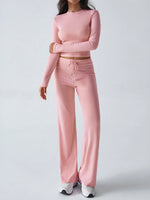Person wearing a pink long-sleeve top and pants set on a light gray background