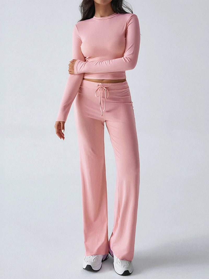 Person wearing a pink long-sleeve top and pants set on a light gray background