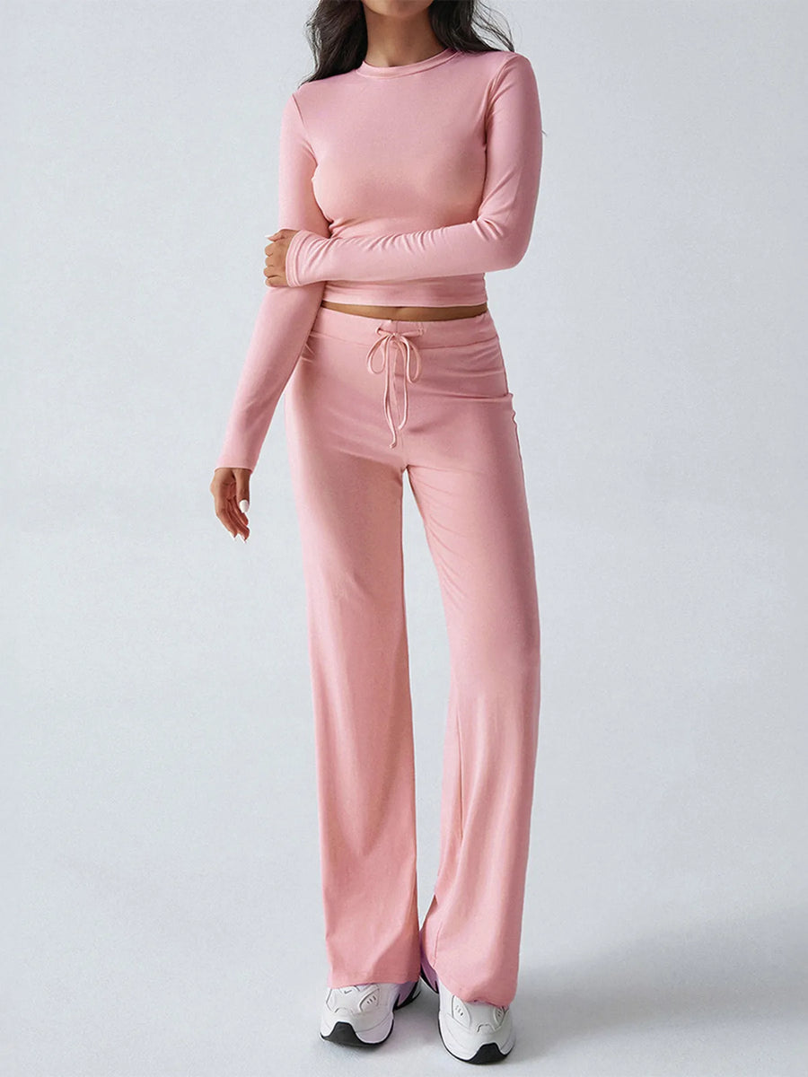 Person wearing a pink long-sleeve top and pants set on a light gray background