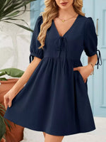 Woman wearing a navy blue dress with puffed sleeves in an outdoor setting.