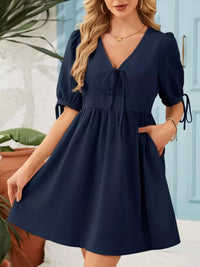 Woman wearing a navy blue dress with puffed sleeves in an outdoor setting.