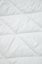 Close-up of a white quilted comforter with diamond pattern