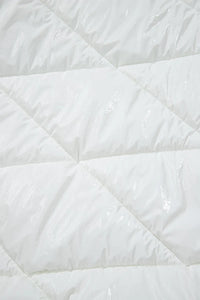 Close-up of a white quilted comforter with diamond pattern