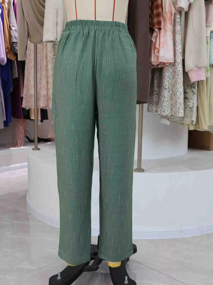 Green wide-leg cropped pants displayed on a dress form mannequin in a clothing boutique setting.