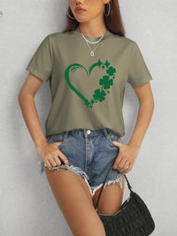 Person wearing a green t-shirt with a shamrock design on a plain background