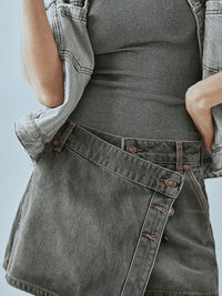 Person wearing a gray denim apron over a black top against a light blue background