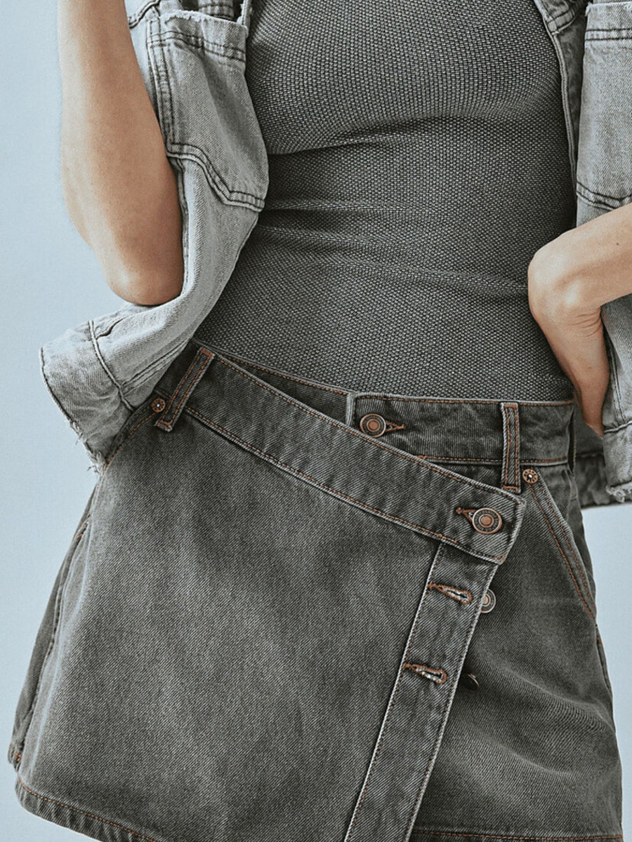 Person wearing a gray denim apron over a black top against a light blue background