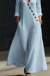 Light blue dress with black buttons worn by a person on a dark background