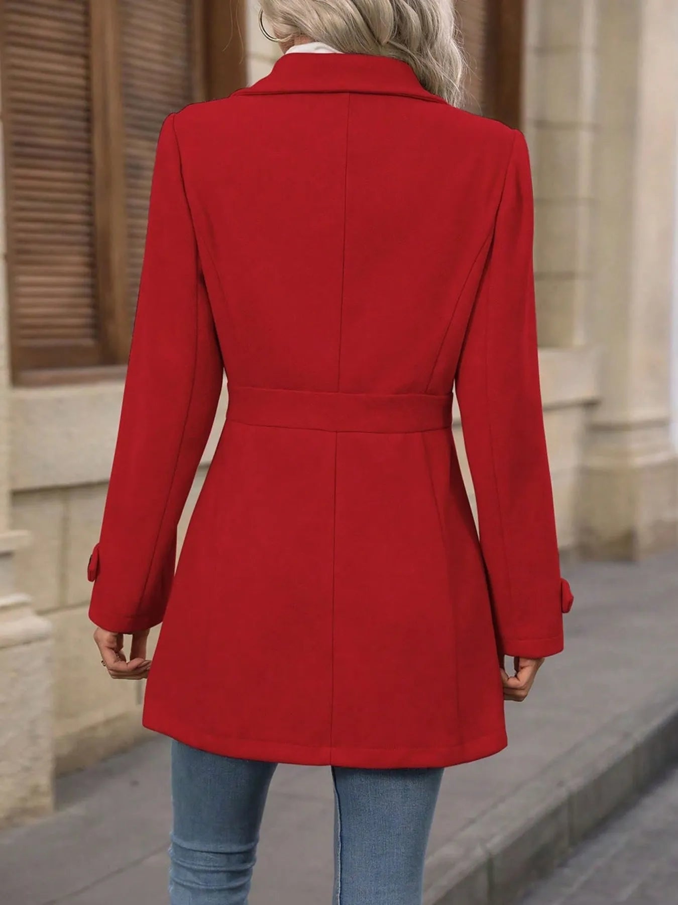 Person wearing a red coat with a neutral background