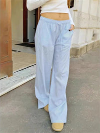 Person wearing light blue wide-leg pants and a white top outdoors.