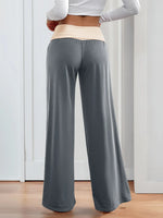 Person wearing gray wide-leg pants and a white long-sleeve top indoors.