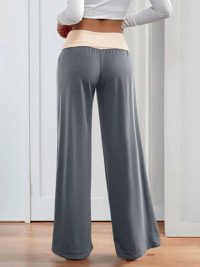 Person wearing gray wide-leg pants and a white long-sleeve top indoors.