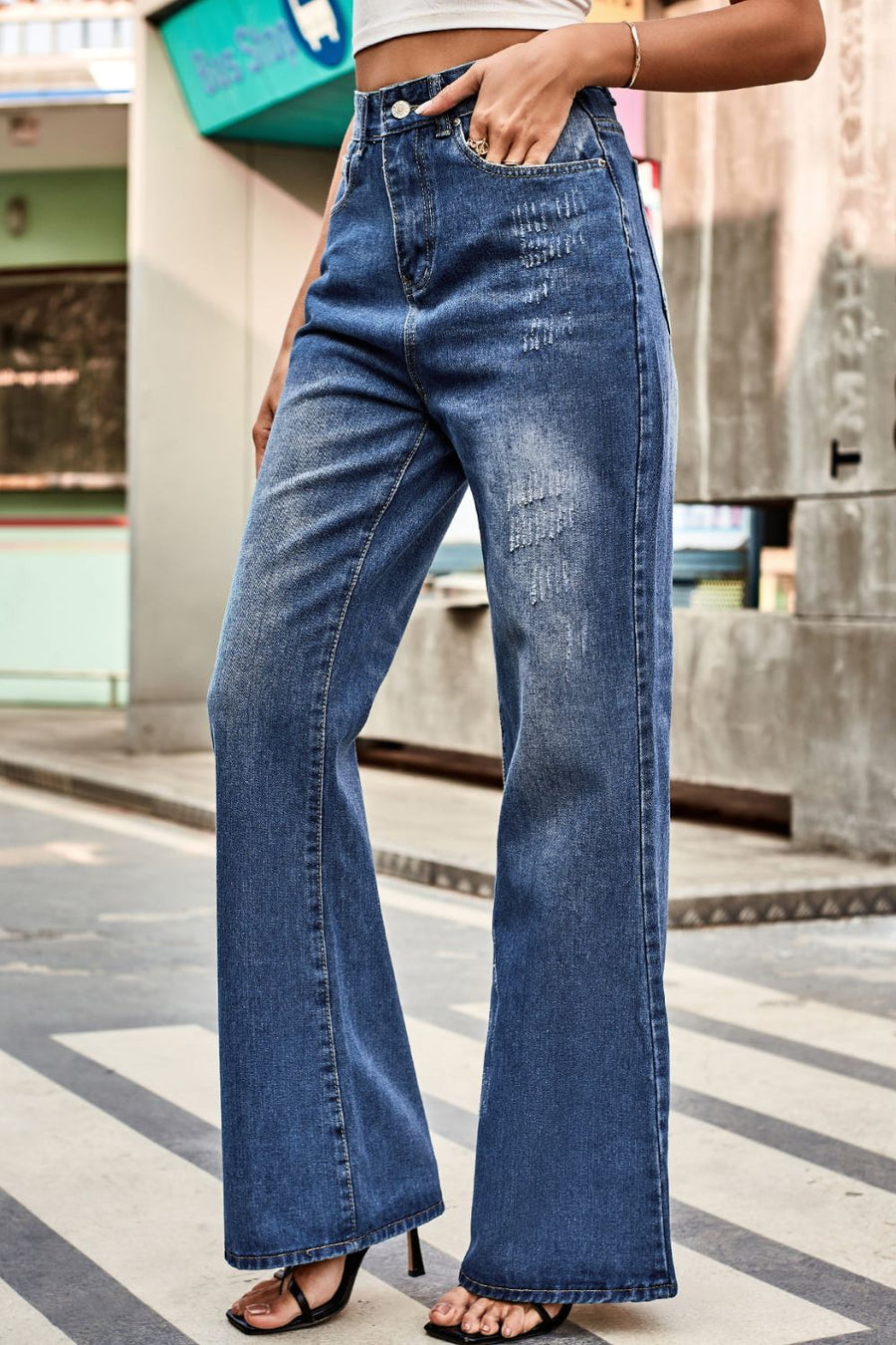 Person wearing blue flared jeans on a city street.