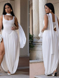 Woman in a white dress with a slit standing outdoors near classical architecture.