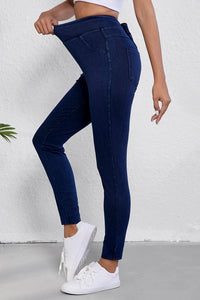 Person wearing blue jeans and white sneakers on a plain background