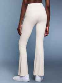 Person wearing white flared pants on a gray background