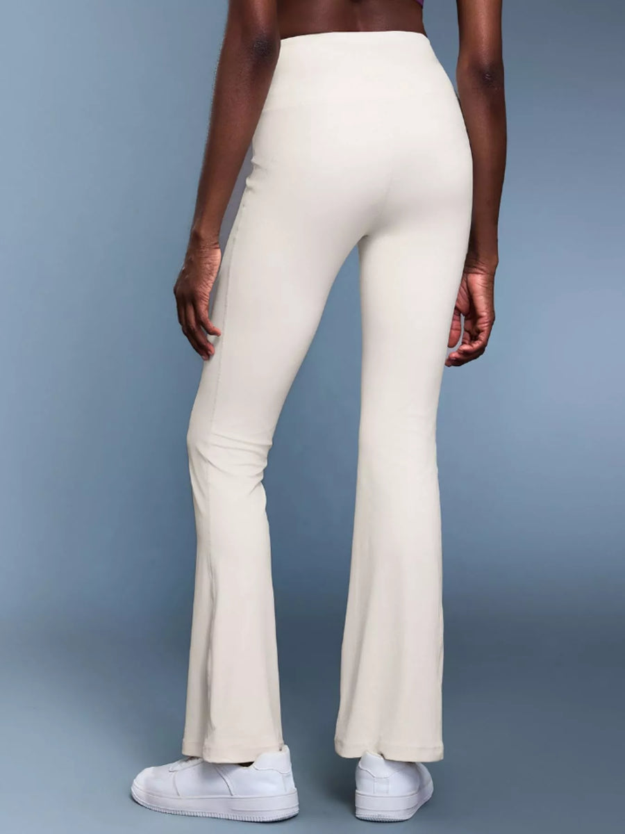 Person wearing white flared pants on a gray background