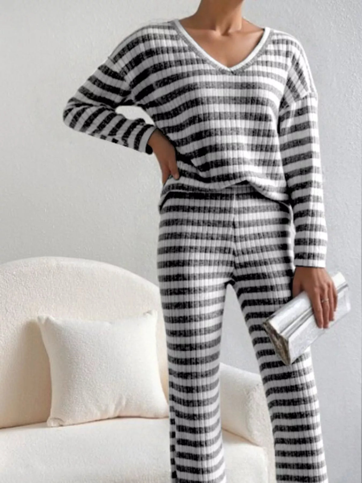 Person wearing a black and white striped pajama set sitting on a couch.