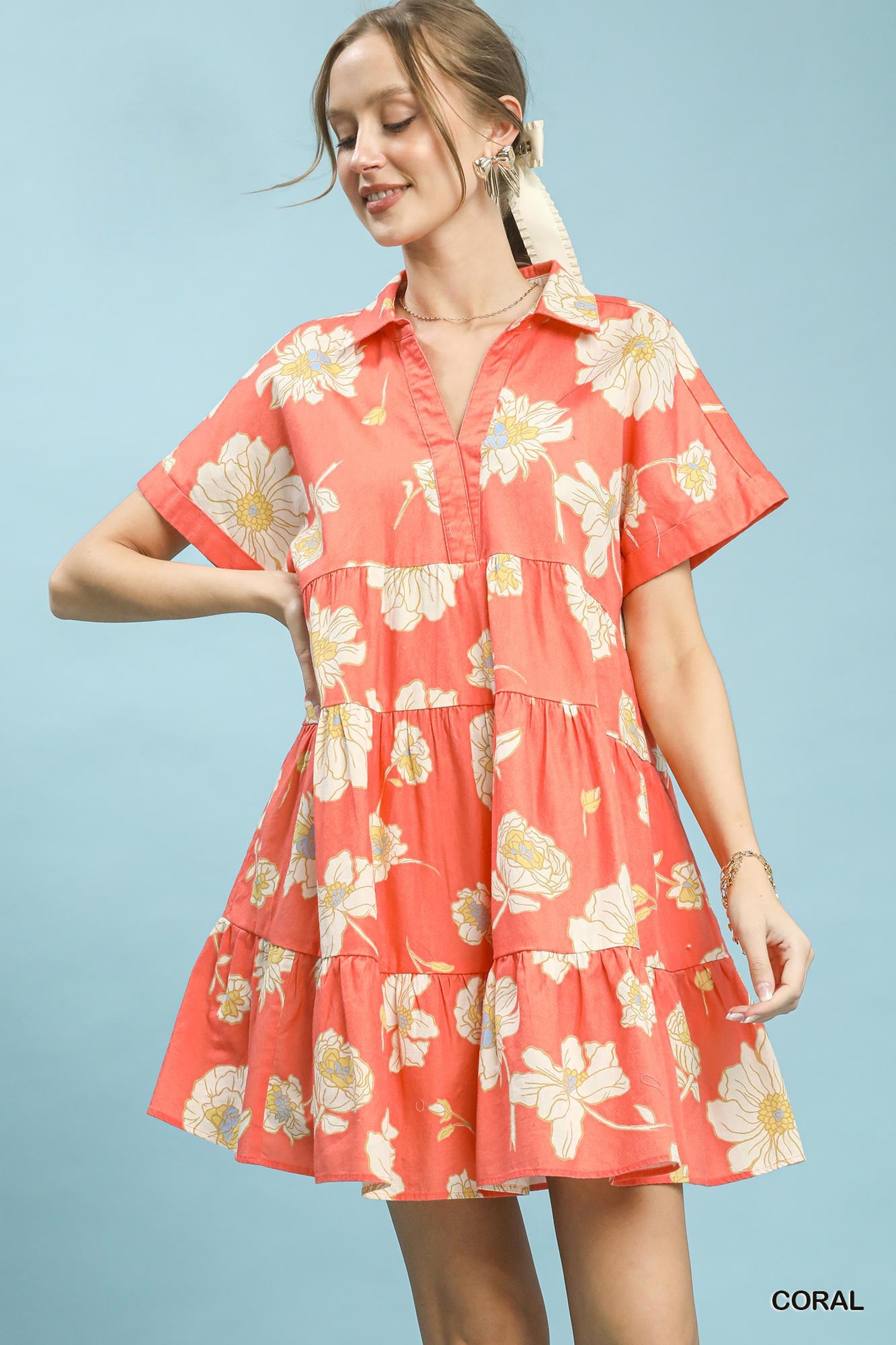 Woman wearing a coral floral dress against a light blue background