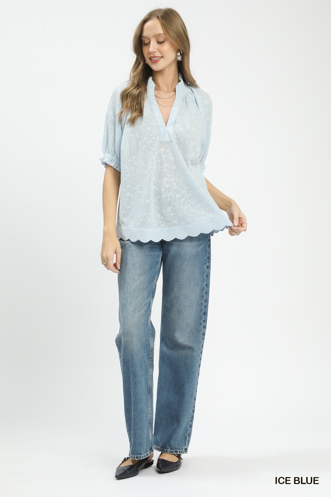 Woman wearing a light blue blouse and jeans on a white background