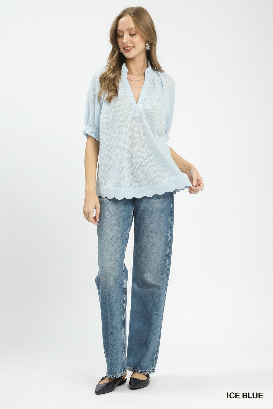 Woman wearing a light blue blouse and jeans on a white background