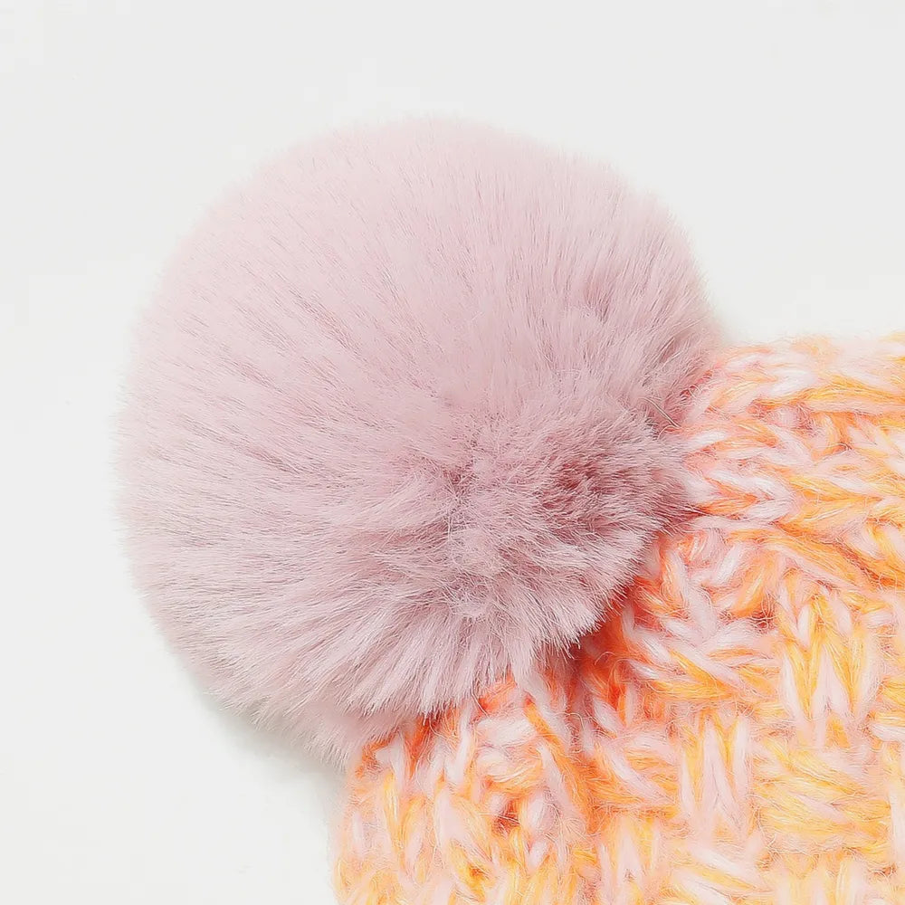 Pink fluffy pom-pom on a textured orange and pink fabric background