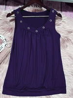 Purple sleeveless dress with button details on a hanger against a fluffy white surface.