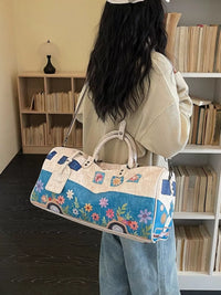 Person holding a floral-patterned duffel bag in a room with bookshelves.