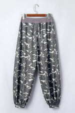 Gray pants with white pattern on a hanger against a white background