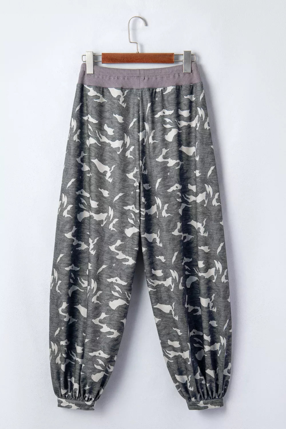 Gray pants with white pattern on a hanger against a white background