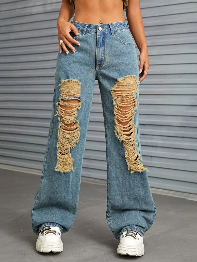 Person wearing ripped blue jeans with a gray background