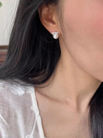 Close-up of a person wearing a pearl earring with a blurred background
