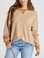 Woman wearing a beige ribbed sweater and blue jeans on a white background