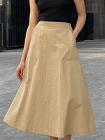 Person wearing a beige skirt and black top on a gray pavement background