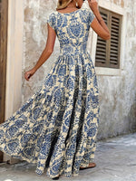 Woman wearing a blue and white floral dress in an outdoor setting.