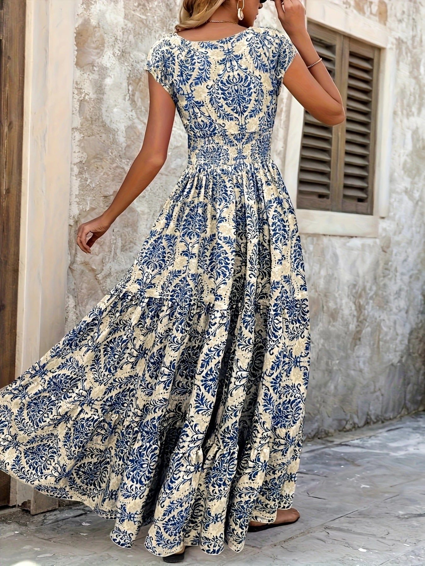 Woman wearing a blue and white floral dress in an outdoor setting.