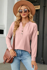 Woman wearing a pink long-sleeve top, blue jeans, and a brown hat with sunglasses outdoors.