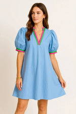 Woman wearing a light blue dress with colorful accents on a beige background