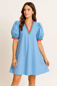 Woman wearing a light blue dress with colorful accents on a beige background