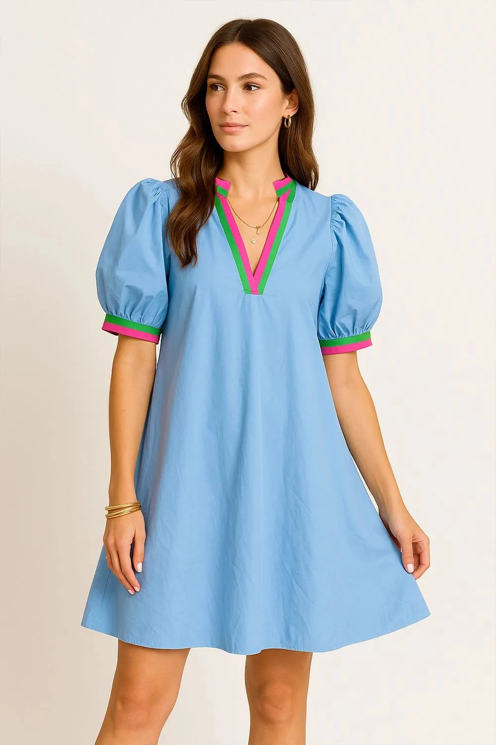 Woman wearing a light blue dress with colorful accents on a beige background