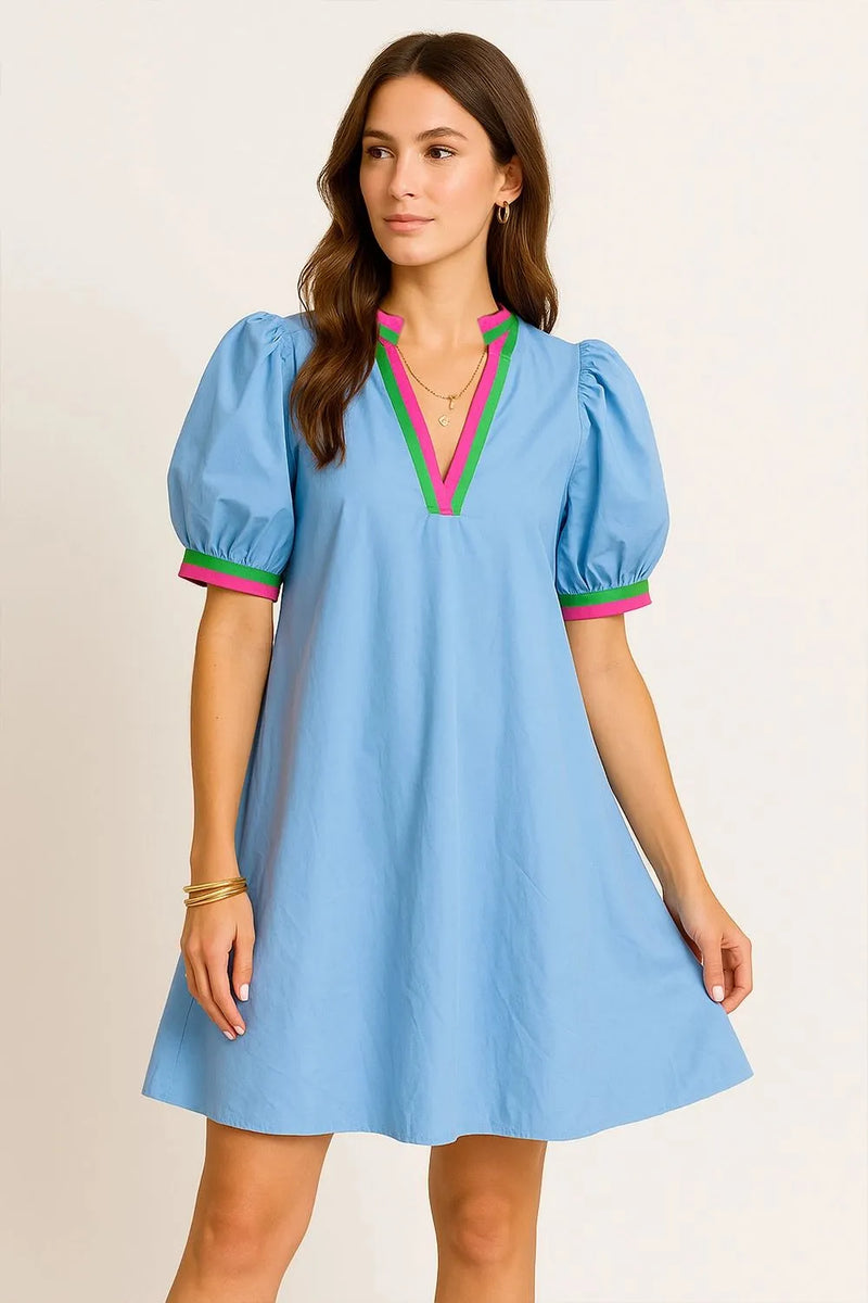 Woman wearing a light blue dress with colorful accents on a beige background