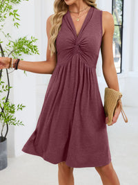 Woman wearing a maroon dress holding a clutch indoors.