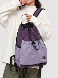 Person holding a purple and black drawstring bag on a white background